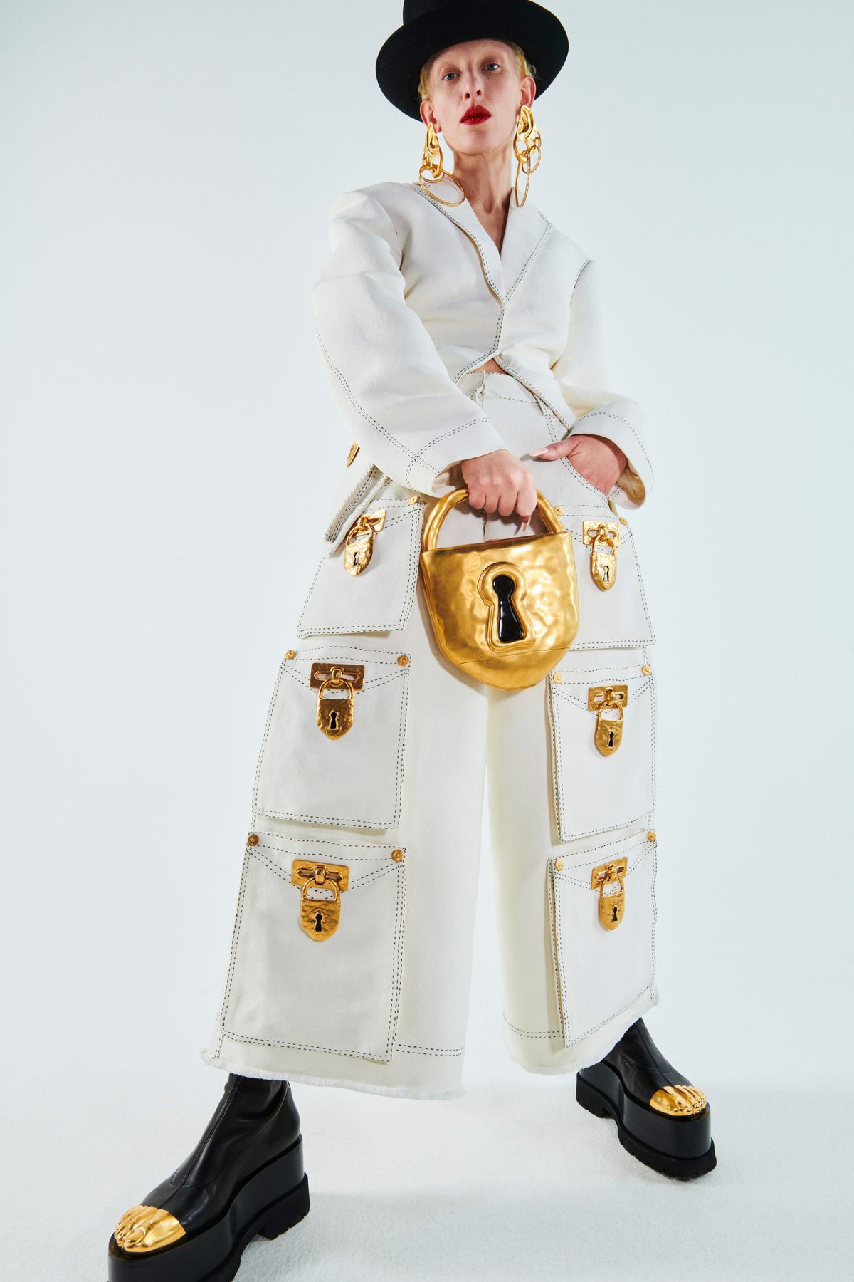 Completo bianco con grandi tasche chiuse da lucchetti dorati e borsa a forma di lucchetto: il surrealismo di Schiaparelli, primavera-estate 2021.